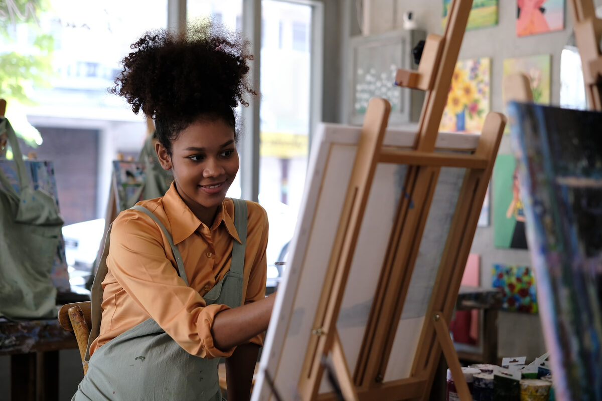 Portrait of featured artist Elena Cruz painting at an easel